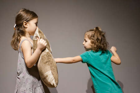 The girl has an older sister in a fit of rage. The eldest is protected by a cushionの写真素材
