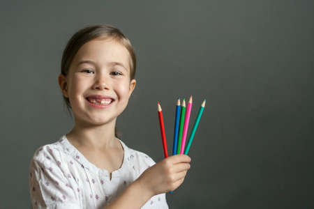 Happy child holding colored pencils and smiling broadly.の写真素材