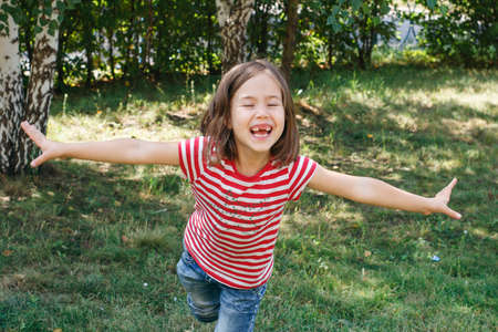 Happy child smiling, arms outstretched. A walk in the spring parkの写真素材