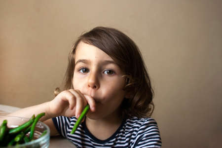 A child plays with food: green beans as a cigaretteの写真素材