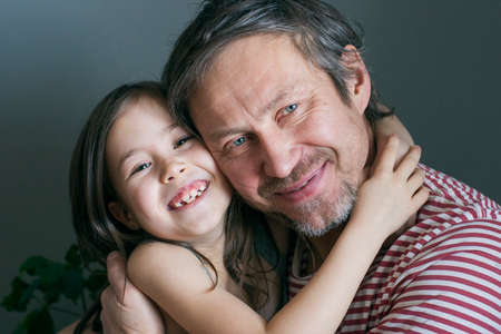 Little smiling girl hugging her beloved smiling grandfatherの写真素材