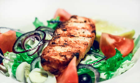 Salad with salmon, tomatoes and quail egg on a white plateの写真素材