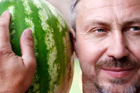 A middle-aged man chooses a ripe watermelonの写真素材