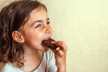 Tanned girl enjoys a slice of milk chocolateの写真素材