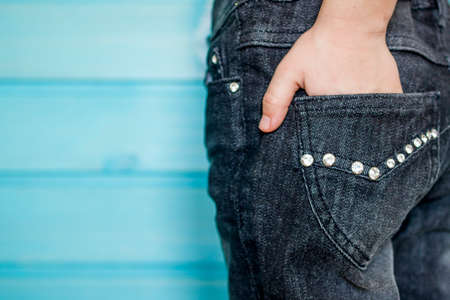 The hand in the back pouch of jeans, trimmed with rhinestones
