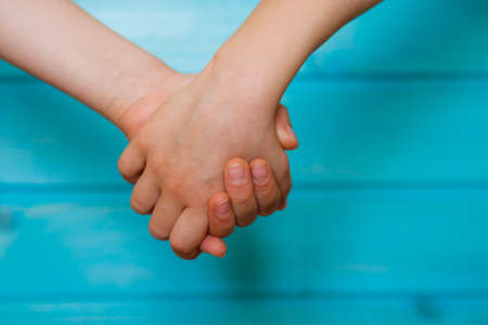 Friends hold hands tightly. Children's friendship close up