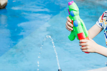 the child plays with water and a water pistol in a fountain