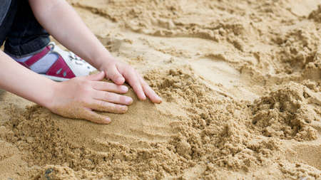 the child is building a tower of sand on the seashoreの写真素材