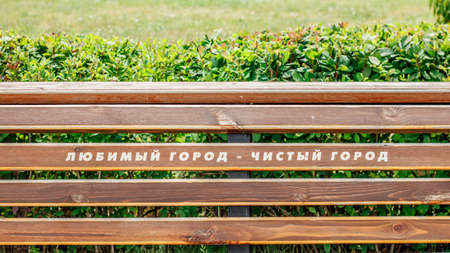 A wooden bench in the city park with the inscription in Russian: Favorite city is a clean cityの写真素材