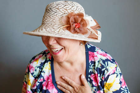 An elderly lady in a hat laughs from the heartの写真素材