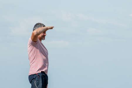 Middle-aged man peering into the distance against the blue sky