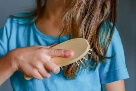 Girl combs long hair with a wooden massage brushの写真素材