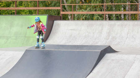 Little girl riding on roller skates in a helmet and knee pads
