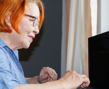 old lady mastering computer and internet at homeの写真素材