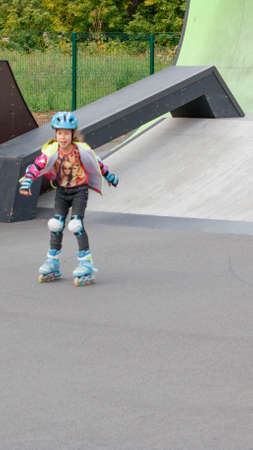Little girl riding on roller skates in a helmet and knee pads