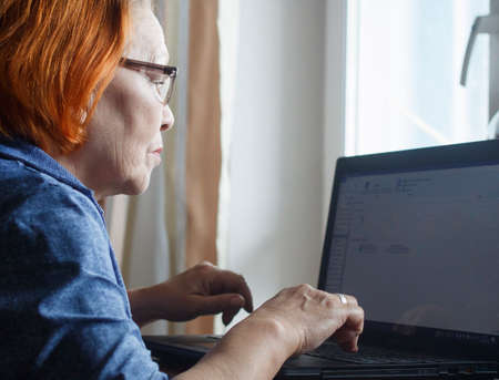old lady mastering computer and internet at homeの写真素材