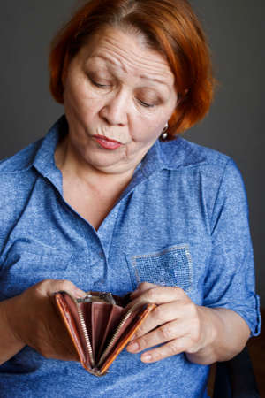 Woman of retirement age with sadness looks into an empty wallet