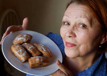 Grandmother with a plate of delicious muffins with raisins