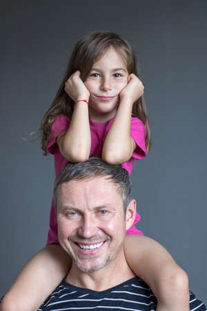 Happy girl sitting on dad's shoulders