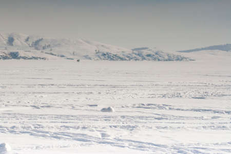 Winter landscape: an icy lake surrounded by mountainsの写真素材