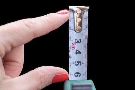 Construction tape measure in female hand. Size mattersの写真素材