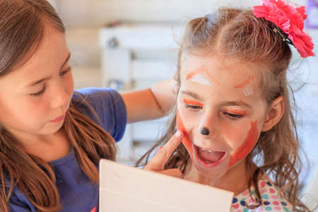 Children consider face painting in a mirror