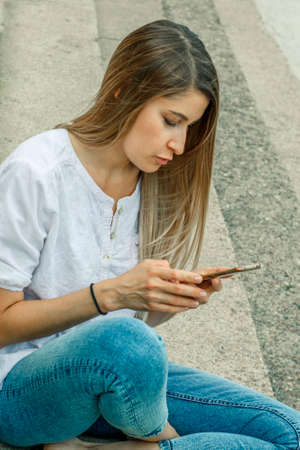 Girl in a white shirt on the steps of the university. The applicant is preparing for the school...