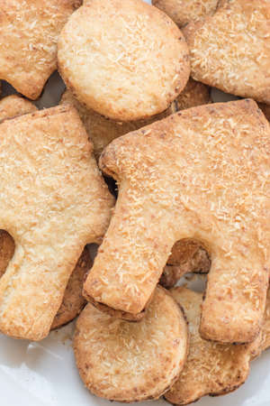 Curly homemade shortbread cookies on a white plate. Rolling pin, forms for cookies on a white table.