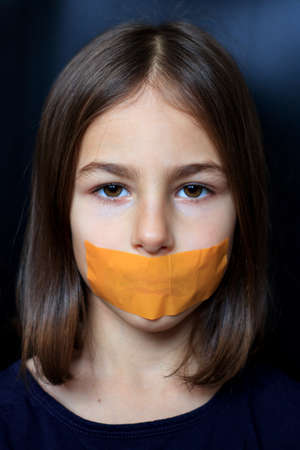 Unhappy girl with sticky tape over her mouth. Violation of human rights.