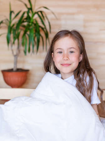 Portrait of a smiling girl waking up early in the morning in a country wooden house.の写真素材