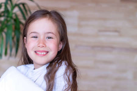 Portrait of a smiling girl waking up early in the morning in a country wooden house.