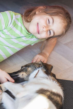 Girl has fun playing on the floor with a dogの写真素材