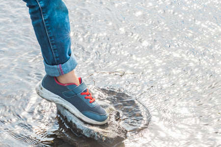 A man in sneakers crosses a clean mountain stream.の写真素材
