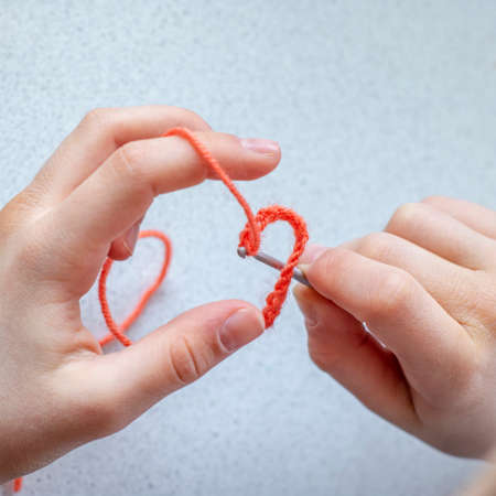 Child girl takes the first steps in learning crochetの写真素材