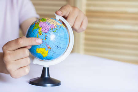 A child twists the globe with his finger, dreaming of traveling around the earthの写真素材