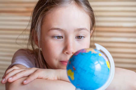 Child girl is smiling and looking at the globe, dreaming about traveling.の写真素材