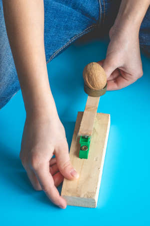 A child shoots a walnut at a target from a handmade catapultの写真素材
