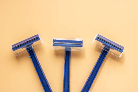 Set of three disposable razors in blue on a beige background. Banner templateの写真素材