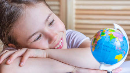 Child girl is smiling and looking at the globe, dreaming about traveling.の写真素材