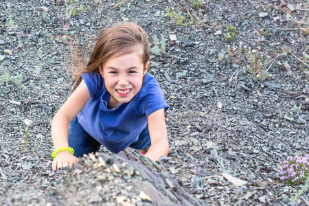 Child girl climbs to the top of the mountainの写真素材