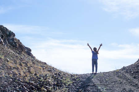 Child girl climbs to the top of the mountainの写真素材