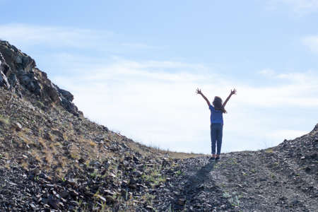 Child girl climbs to the top of the mountainの写真素材
