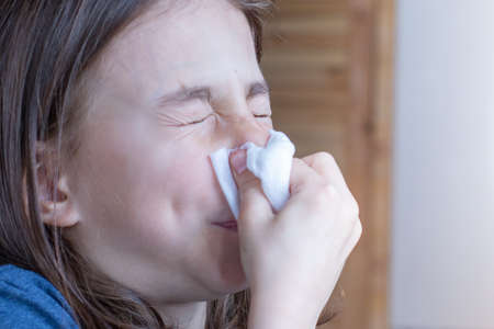 Baby girl blowing her nose in a white handkerchiefの写真素材