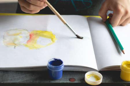 The child paints at home with bright colors in the albumの写真素材
