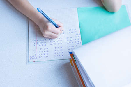 The child solves mathematical examples of elementary school in a notebookの写真素材