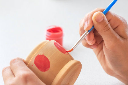 A child paints a wooden blank of a nesting doll. Children's craftsの写真素材