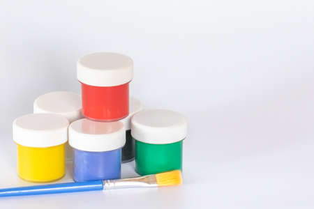 Jars of gouache paints with a brush on a white background. Banner template