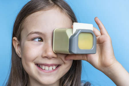 Child girl looks at old photos through a diascope. Banner template on pink background.の写真素材