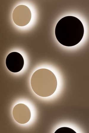 Round LED lamps without decor are placed on a light wall and illuminate the space