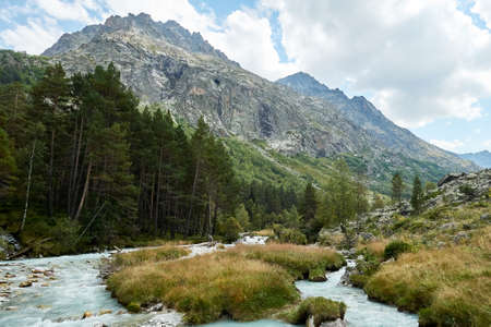 Mountain river water landscape. Alps. The cloudy sky in clear sunny day. Warm summer. Time for pedestrian tourism and family holiday with friends. Blue sky. Travel.の写真素材